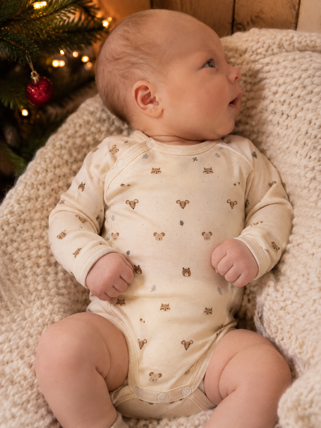 Nyfødt baby i Hust and Claire fold-over body Forest ligger i kurv ved juletreet