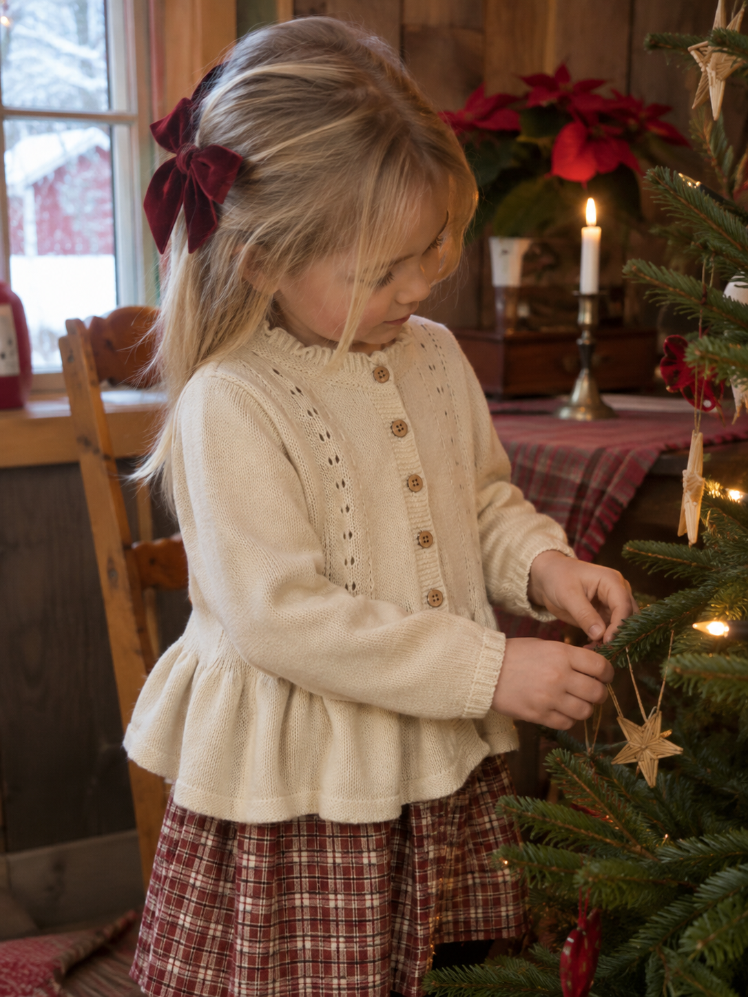 Jente i kremhvit Lil Atelier Ramla strikkecardigan pynter juletreet