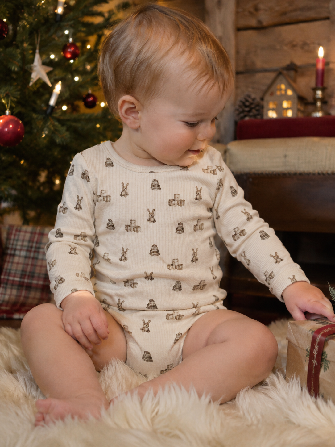 Baby i Lil Atelier Gavo body med leker-trykk ved juletreet